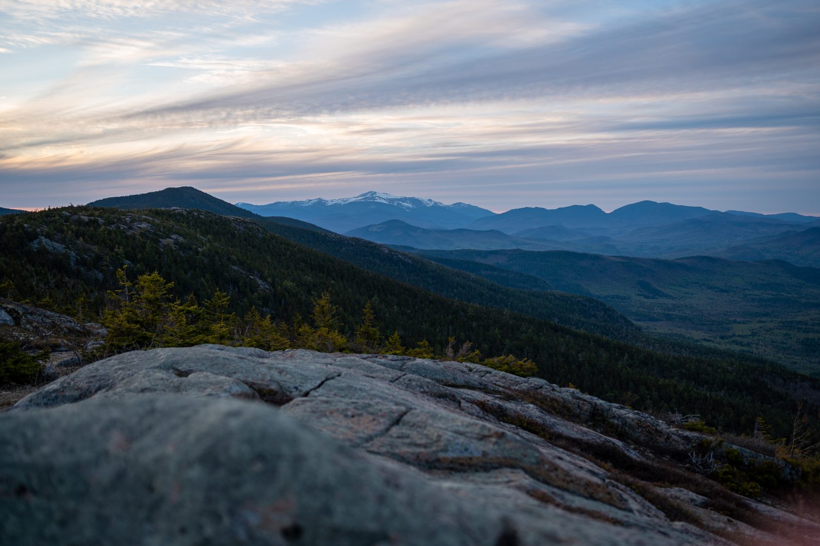 The Mount Washington Valley seen from a granite ledge, with snow-capped Mount Washington in the distance.