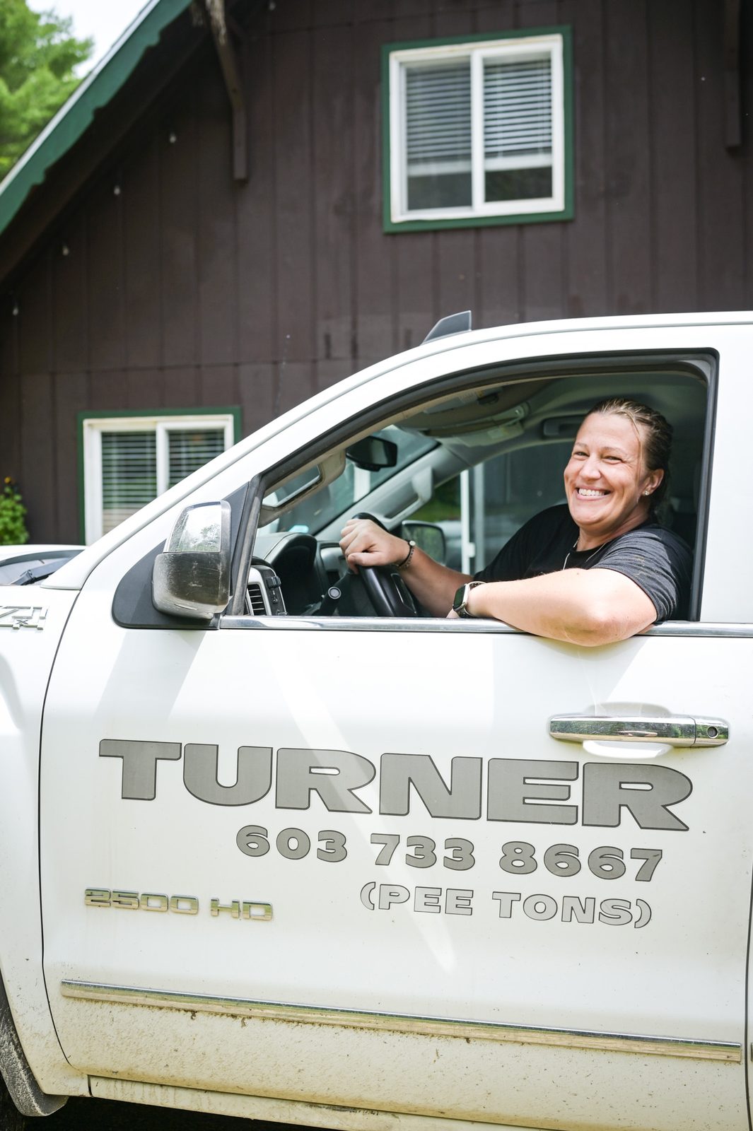 A smiling Turner Septic team member at the wheel of a branded service pickup.